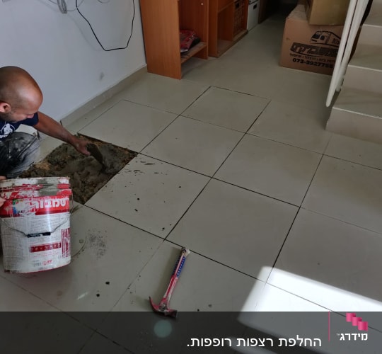 אדם מתקין אריחי רצפה עם מלט ודלי